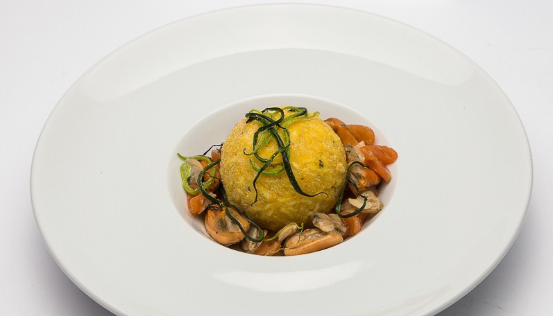 Arancina al baccalà con profumo di arancia su rosticciata di frutti di mare e filetti di campo